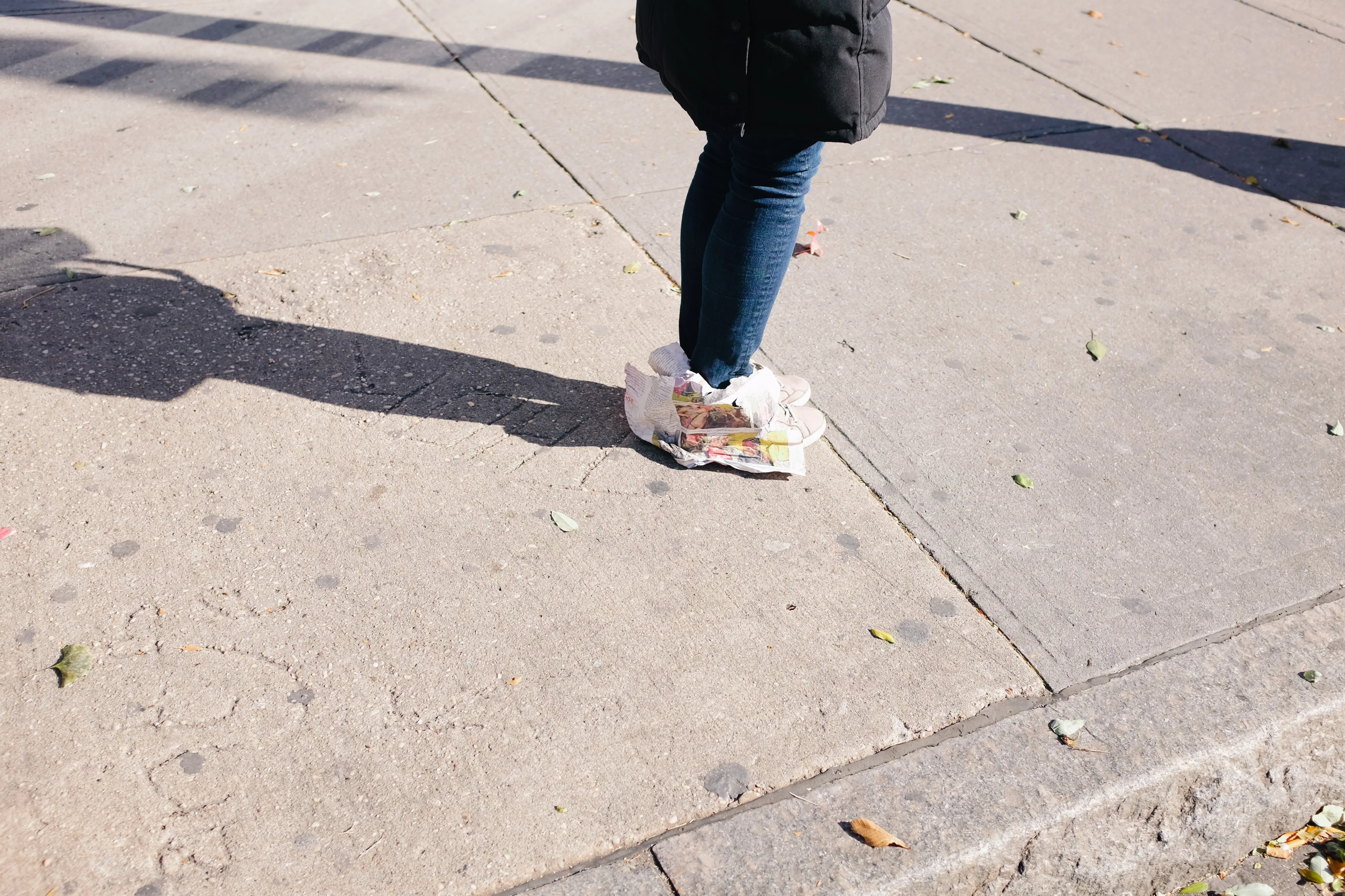 Close-up photograph of a person walking on sunlit pavement